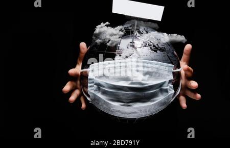 Sur fond noir, les mains d'enfant tenant globe couvert de masque de protection médicale notre planète sous les nuages ont besoin d'aide. Éclosion de pandémie COVID-19 Banque D'Images