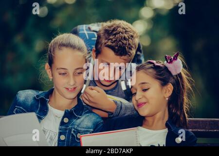 Retour à l'école. Les enfants avec des sacs à dos ont du plaisir, de parler, de lire un livre.Groupe d'écoliers élémentaires ayant une discussion sur les devoirs pendant leur déplacement Banque D'Images