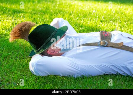 homme bavarois allongé dans l'herbe et portant un masque de protection Banque D'Images