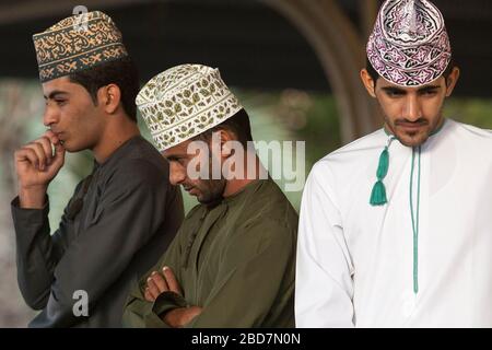 Les hommes et les garçons omanais s'élèvent et se aggle pour le bétail sur le marché du bétail du vendredi dans l'ancien souk de Nizwa en Oman Banque D'Images
