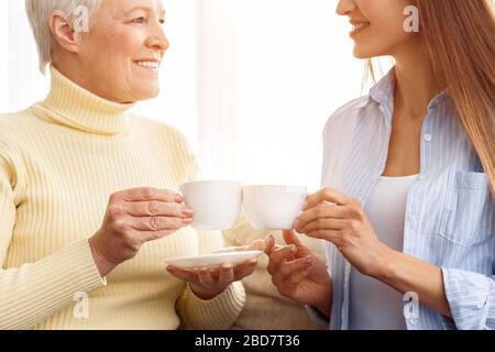 Bonne mère et fille qui toaster le thé, en prenant le petit déjeuner Banque D'Images