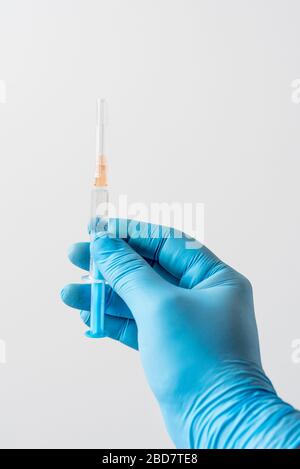 Main d'un médecin dans un gant bleu tenant une seringue. Antécédents médicaux. Le médecin qui tient une seringue pour la vaccination. Banque D'Images