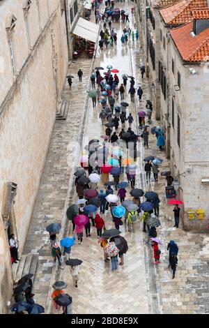 Vue aérienne des touristes avec parasols marchant sur le Stradun dans oldtown, Dubrovnik en Croatie. Banque D'Images