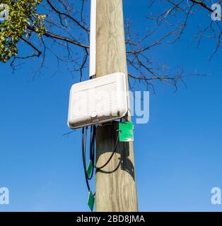 Borne de rue à fibre optique sur un montant électrique avec plusieurs terminaisons FTTH câbles noirs Banque D'Images