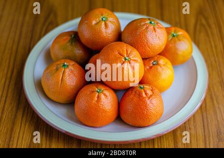 Des fruits orange mandarins frais sur une assiette dans une photo de vie. Banque D'Images