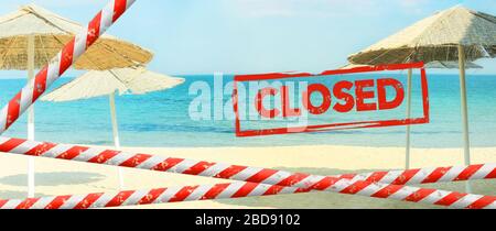 Inscription rouge « fermée » sur un fond flou d'une plage désertée. La plage est fermée avec un ruban rouge barrière. Concept: Vacances annulées due Covid-1 Banque D'Images