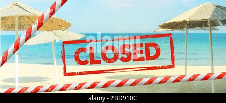 Inscription rouge « fermée » sur un fond flou d'une plage désertée. La plage est fermée avec un ruban rouge barrière. Concept: Vacances annulées due Covid-1 Banque D'Images