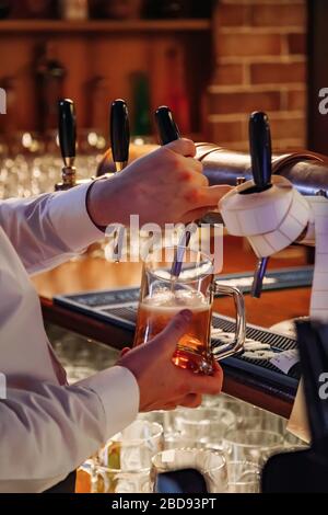 Barman versant de la bière pression de la grue dans le verre dans le pub Banque D'Images