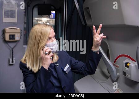 08 avril 2020, Hessen, Francfort-sur-le-Main: Un agent de vol avec masque facial accueille les passagers d'un Boeing 747 de Lufthansa après l'atterrissage à l'aéroport de Francfort. Avec un total de près de 350 passagers et membres d'équipage, l'avion avait retiré 25 heures plus tôt en Nouvelle-Zélande pour ramener en Allemagne les personnes qui y avaient été bloquées en raison de la pandémie de corona. Plusieurs autres avions doivent suivre dans les jours à venir. Photo: Boris Roessler/dpa Banque D'Images