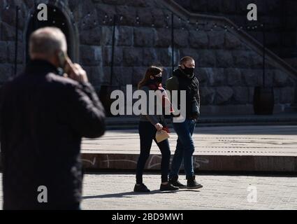 Les gens qui marchent le long de la rue principale Khreshchatyk portant des masques de visage comme mesure préventive, pendant la pandémie du virus corona.le Cabinet des ministres de l'Ukraine a adopté une résolution sur le renforcement des mesures de quarantaine. Le gouvernement interdit de se rassembler dans les rues en groupes de plus de deux personnes, en marchant dans les parcs, les zones de parc forestier et les remblais, en visitant les terrains de sport et de jeux. Banque D'Images