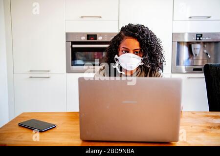Rotterdam, Pays-Bas. 7 avril 2020. Une femme portant un masque de visage comme mesure de protection travaille à sa maison.le gouvernement néerlandais a commandé la fermeture de toutes les écoles et de tous les bureaux jusqu'à nouvel ordre afin de contrôler la propagation du Coronavirus COVID-19. Les étudiants doivent être scolarisés à la maison avec des moyens numériques tels que des ordinateurs portables, des tablettes numériques ou des téléphones mobiles. Crédit: SOPA Images Limited/Alay Live News Banque D'Images