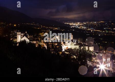 Vue aérienne de la ville d'Assise (Ombrie, Italie) et de la vallée la nuit, avec lumières de la ville et église Santa Chiara Banque D'Images