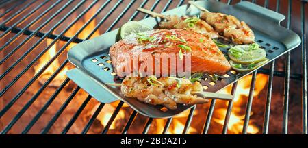 Assortiment de fruits de mer frais sur un barbecue avec des brochettes de crevettes ou de scampi et une grande partie de filet de saumon assaisonné d'herbes et de citron Banque D'Images