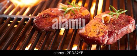 Bannière Panorama avec steak de bœuf cru sur un barbecue en sirotant des coals chauds flamboyants dans une vue rapprochée avec espace de copie Banque D'Images