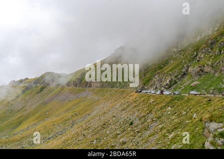 La route qui traverse les montagnes de Fagaras vues d'en haut parmi le brouillard, Transfagarasan, Roumanie Banque D'Images