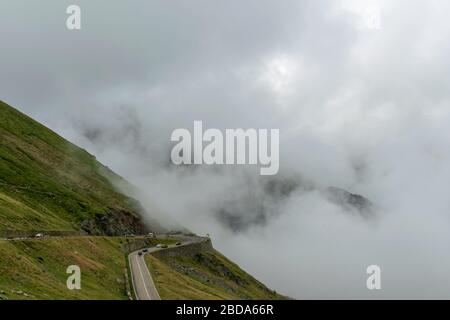 La route qui traverse les montagnes de Fagaras vues d'en haut parmi le brouillard, Transfagarasan, Roumanie Banque D'Images