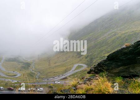 La route qui traverse les montagnes de Fagaras vues d'en haut parmi le brouillard, Transfagarasan, Roumanie Banque D'Images