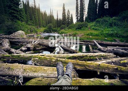 Les jambes de l'homme dans le suivi des chaussures et vue sur le bois et lac de montagne. Voyage en plein air concept. Banque D'Images