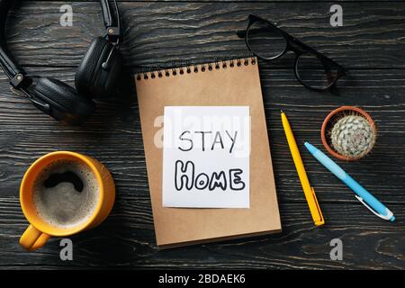 Cahier avec inscription rester à la maison sur fond en bois. Quarantaine Banque D'Images