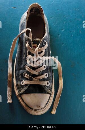 Photo rapprochée haute résolution d'une sneaker bleue à l'ancienne et portée sur fond bleu avec espace de copie. Banque D'Images