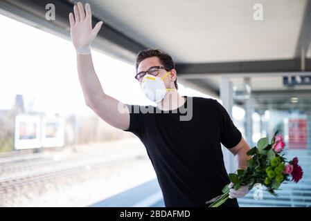 Un homme prend quelqu'un à la gare dans une ère de virus corona avec un masque respiratoire et des gants en caoutchouc Banque D'Images