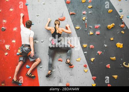 deux athlètes grimpent sur une roche raide, grimpant sur un mur artificiel à l'intérieur. Sport extrême et concept de bouldering Banque D'Images