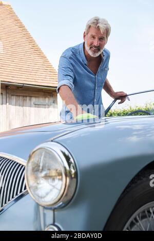 Portrait d'homme mûr restauré Polissage Voiture de sport classique dehors à la maison Banque D'Images