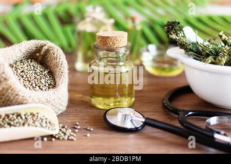 Bouteilles d'huile de chanvre avec graines de cannabis et feuilles sèches sur table en bois blanc. Huile médicale CBD. Concept de médecine alternative. Banque D'Images