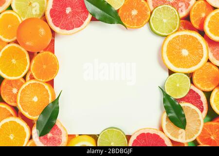 Couche plate d'agrumes comme la chaux, le citron, l'orange et la mandarine avec des feuilles d'orange sur la table faisant un cadre Banque D'Images