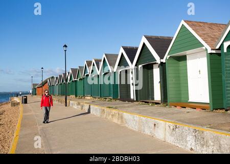 Personne marchant devant les huttes de plage, Gurnard, île de Wight, Royaume-Uni Banque D'Images