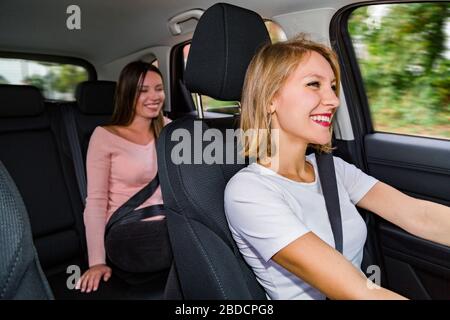 Le conducteur féminin conduit la voiture avec le passager et les sourires Banque D'Images