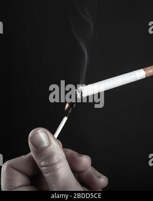 éclairage d'une cigarette avec une allumette brûlante en noir et blanc. Banque D'Images