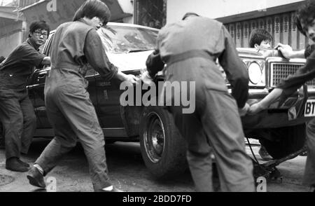 Les services d'urgence, y compris les pompiers, assistent à un incendie de bâtiment dans la rue Kennedy, de Queen's Road East sur l'île de Hong Kong en 1979, en tant qu'équipe de travailleurs en salle, tentent de mettre une voiture Chrysler Premier en sécurité. Photo de Tony Henshaw Banque D'Images