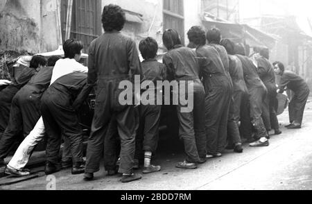 Les services d'urgence, y compris les pompiers, assistent à un incendie de bâtiment dans la rue Kennedy, de Queen's Road East sur l'île de Hong Kong en 1979, en tant qu'équipe de travailleurs en salle, tentent de heurter une voiture à la sécurité. Photo de Tony Henshaw Banque D'Images