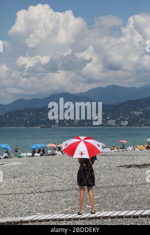 16.07.2018, Batumi, Adjaria, Géorgie - Femme debout sur la plage avec un parapluie dans les couleurs nationales de la Géorgie. 00S180716D027CAROEX.JPG [MODÈLE Banque D'Images