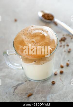 La crème au café Dalgona avec du lait dans une tasse en verre avec cuillère à l'arrière-plan Banque D'Images