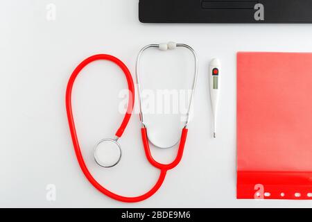Thermomètre médical stéthoscope rouge sur table blanche. Médecins équipement professionnel sur l'espace de travail. Concept médical de santé. Rendez-vous avec un médecin Banque D'Images