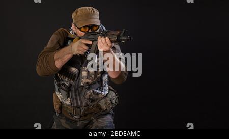 Soldat mercenaires avec un pistolet visant l'ennemi. Gros plan sur un fond sombre. Concept moderne d'armée privée. Banque D'Images