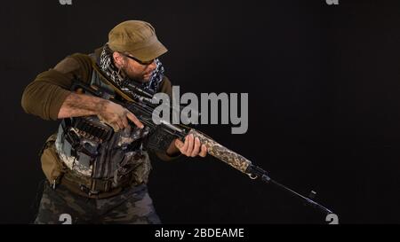 Soldat mercenaires avec un fusil à fusil à niper sur un fond sombre. Concept moderne d'armée privée. Banque D'Images