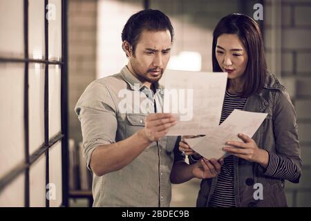 jeunes entrepreneurs asiatiques homme d'affaires et femme d'affaires regardant un document ayant une discussion au bureau Banque D'Images