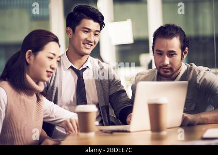équipe de trois jeunes entrepreneurs asiatiques se réunissent au bureau avec une discussion utilisant un ordinateur portable au bureau Banque D'Images