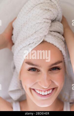Portrait d'une femme souriante avec tête enveloppée d'une serviette Banque D'Images