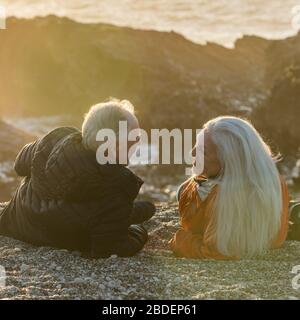 Couple senior profitant du coucher de soleil sur la plage Banque D'Images