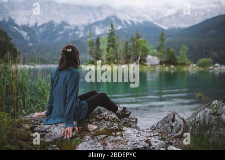 Allemagne, Bavière, Eibsee, jeune femme assise sur le rocher au bord du lac Eibsee dans les Alpes bavaroises Banque D'Images