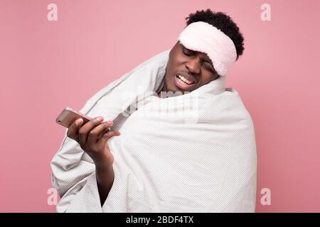 Un homme afro-américain endormi regardant son phine irrita la tenue couverture Banque D'Images