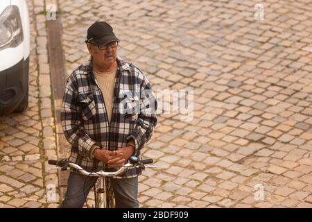 Olhão, Portugal, 8 avril 2020. Un homme priant devant l'église, avec les rues pratiquement désertes, à la suite de l'éclosion du Coro Banque D'Images