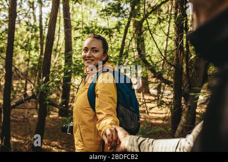 Un couple heureux lors d'un voyage de camping en marchant dans la forêt. Femme tenant main de son homme et marchant dans la forêt. Banque D'Images
