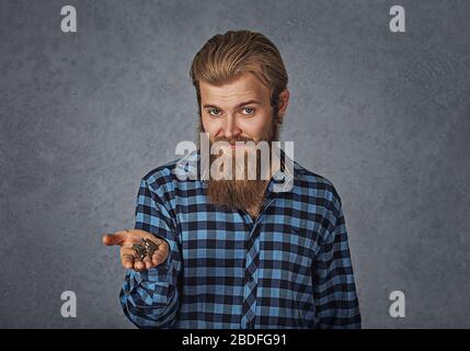 Gros plan portrait d'un jeune homme barbu brutal tenant donnant des clés de maison d'automobile isolé fond gris Banque D'Images