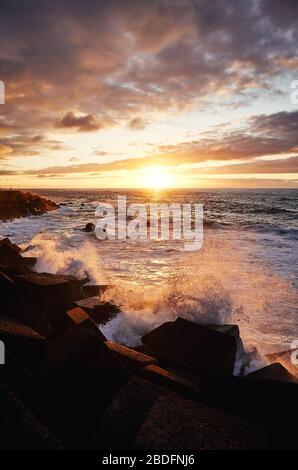 Scenic coucher de soleil avec des vagues se brisant sur les rochers, Puerto de la Cruz, Tenerife, Espagne.