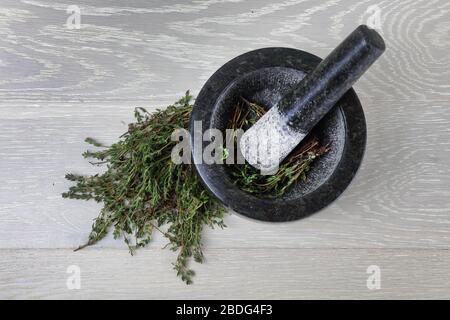 Vue de dessus du thym frais sur la surface du bois et du mortier et du pilon Banque D'Images